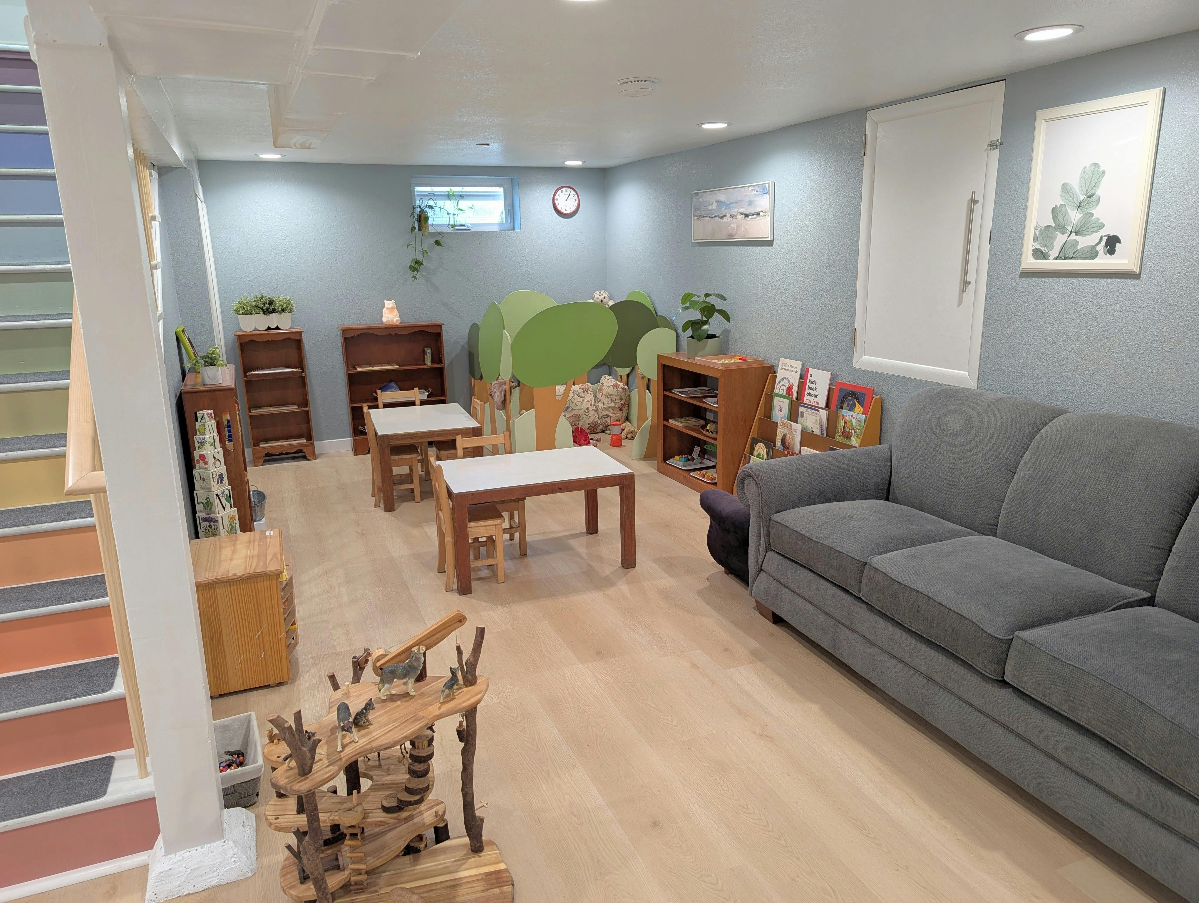 Playroom with small tables and chairs, bookshelves, and a gray sofa