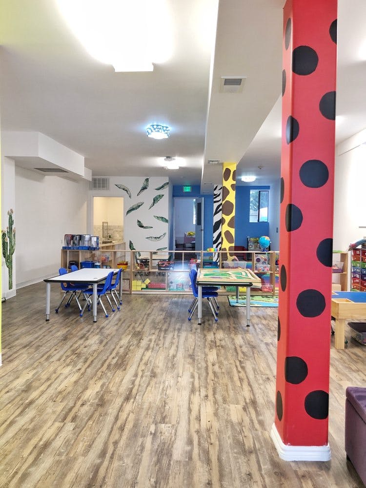 Classroom with small tables and chairs, colorful pillars, and play areas