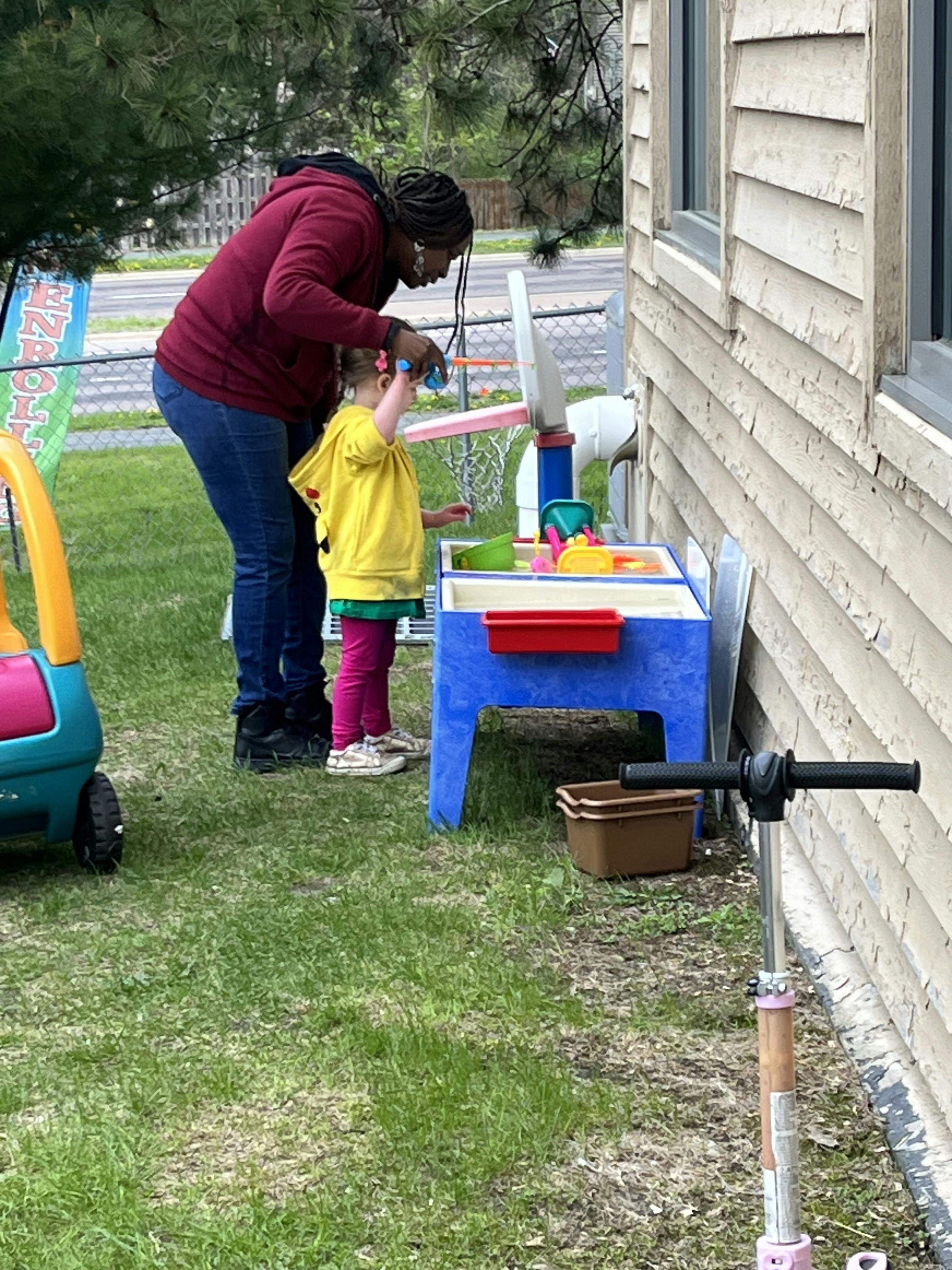 Adult and child playing at a water table outdoors