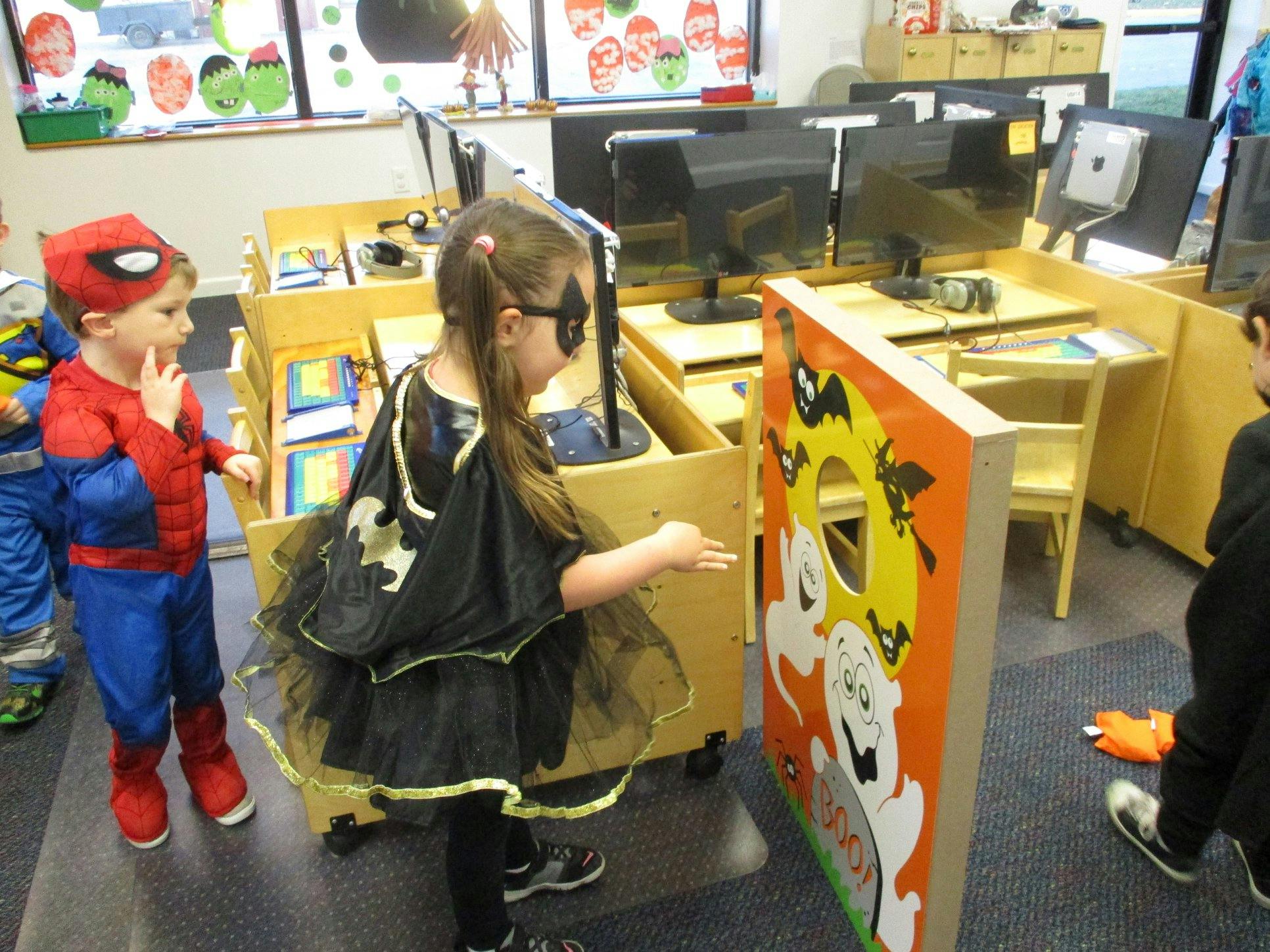 Child in Spiderman costume and child in Batgirl costume playing a game