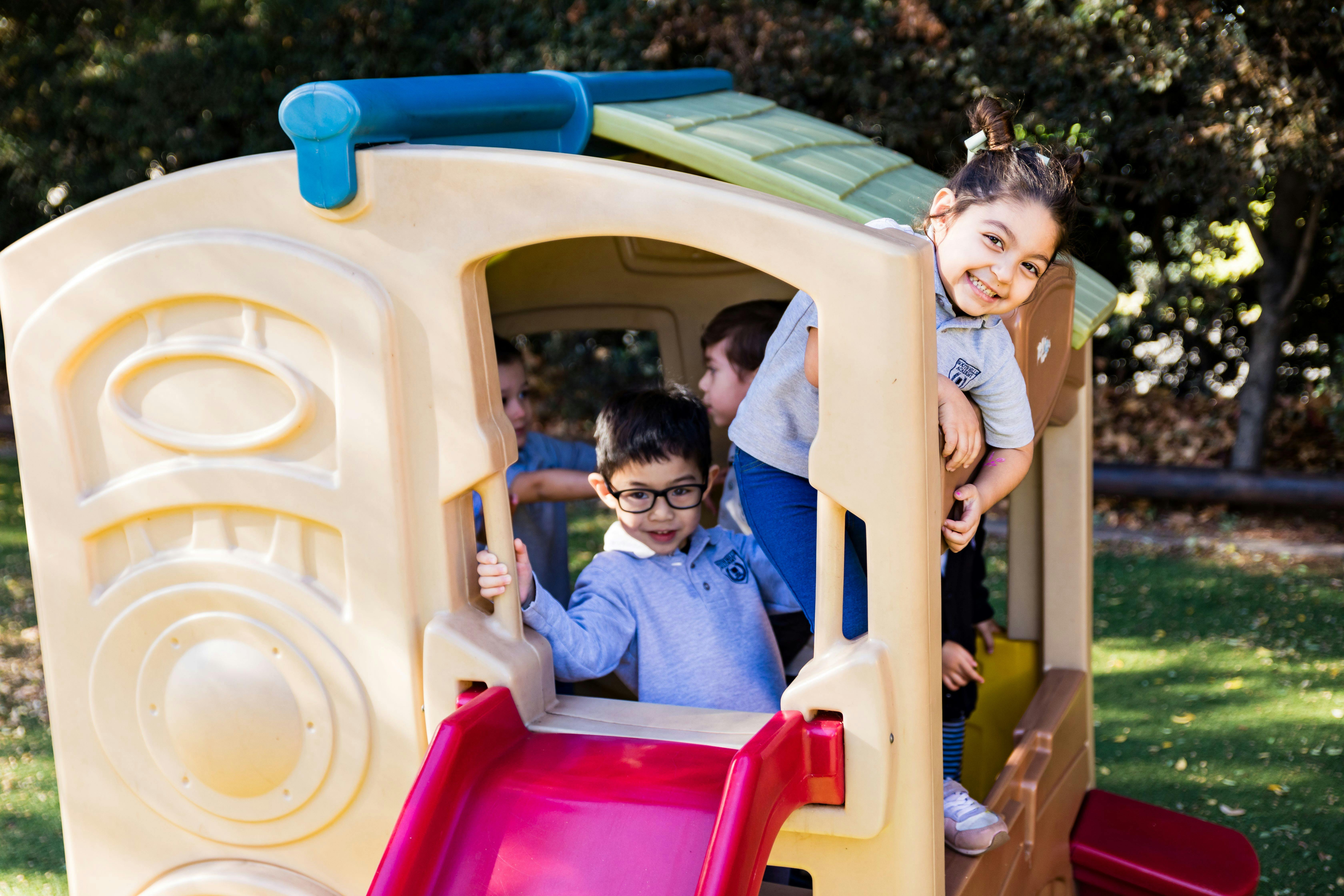 Children playing on a plastic playhouse with a slide