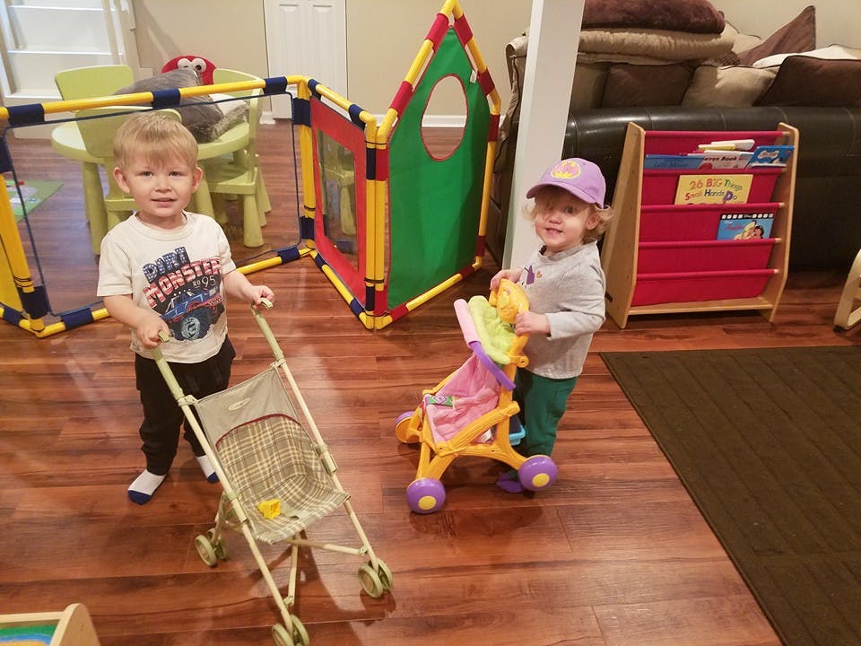 Two children playing with toy strollers indoors