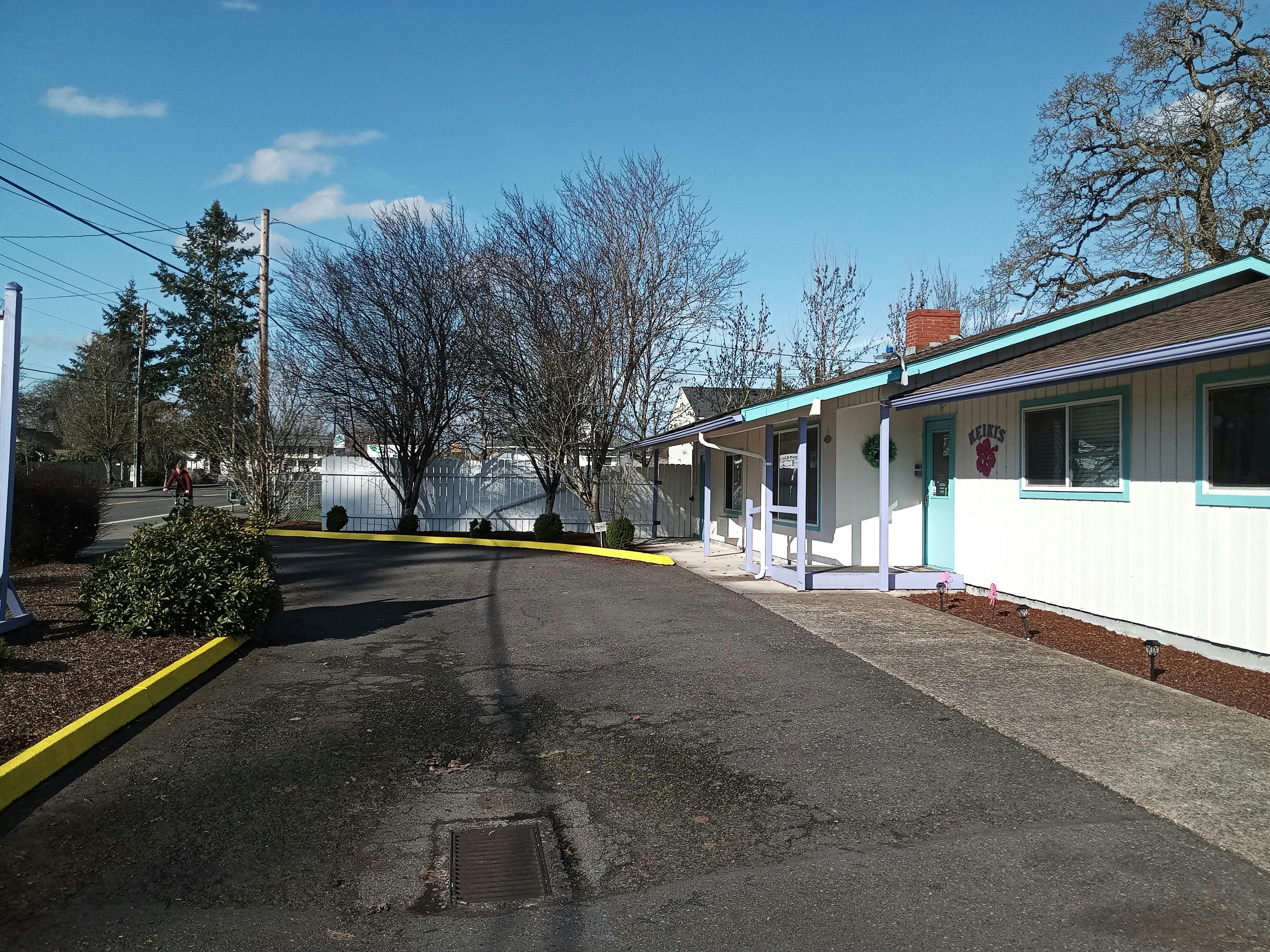 Paved driveway leading to a white building with a porch