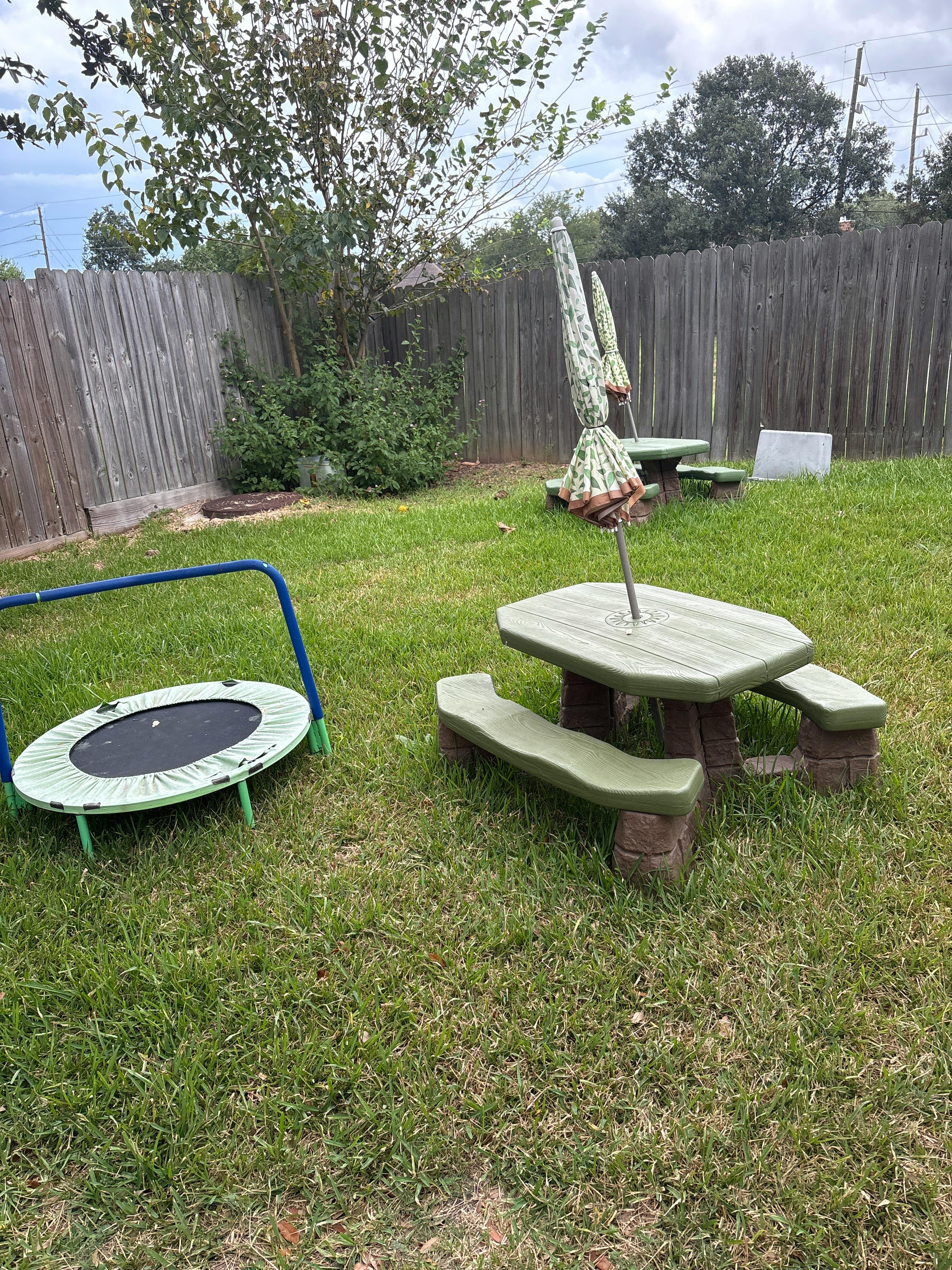 Small table with umbrella and mini trampoline in a backyard