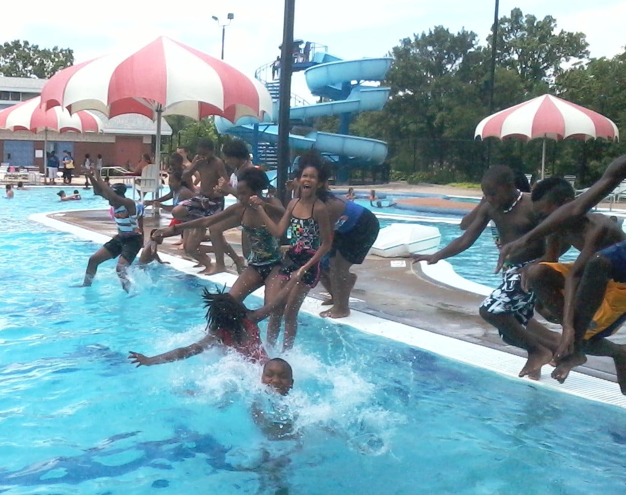 People jumping into a swimming pool