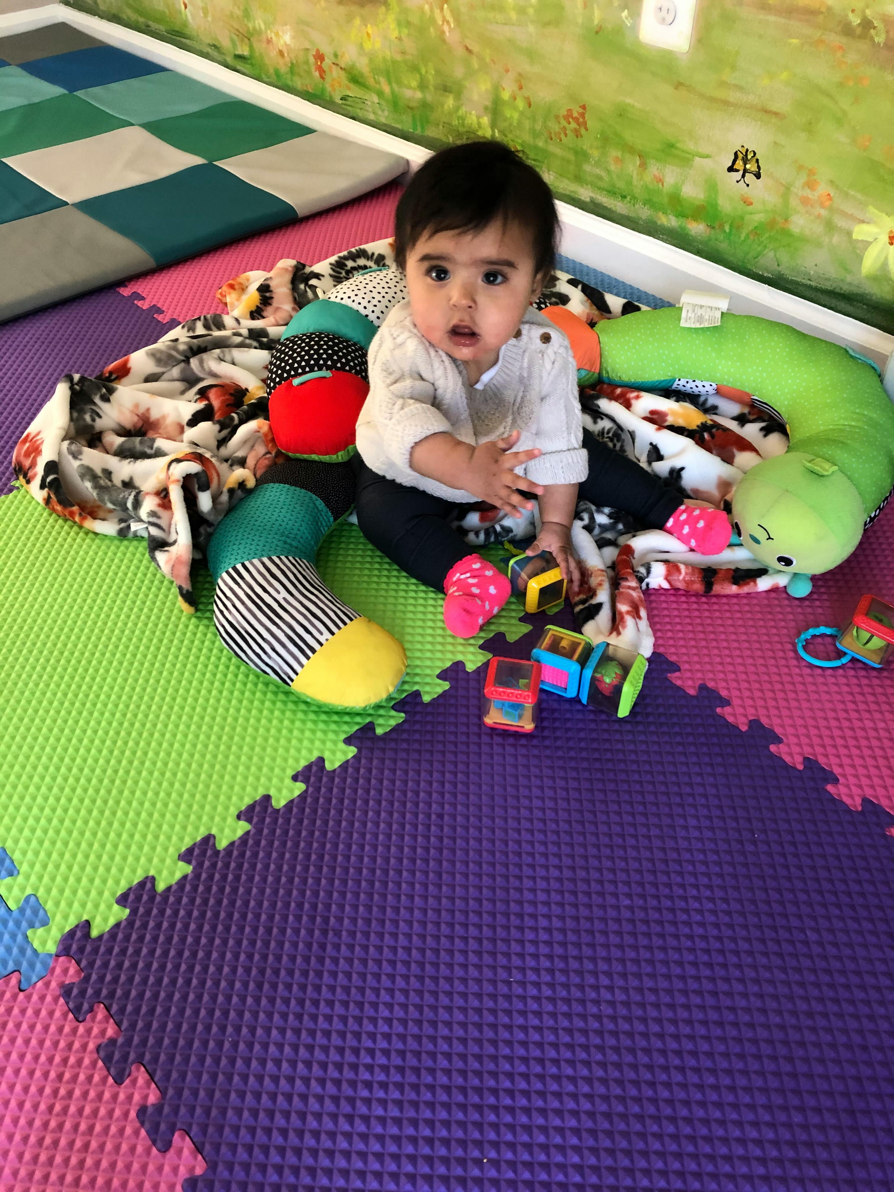 Child sitting on a playmat with toys