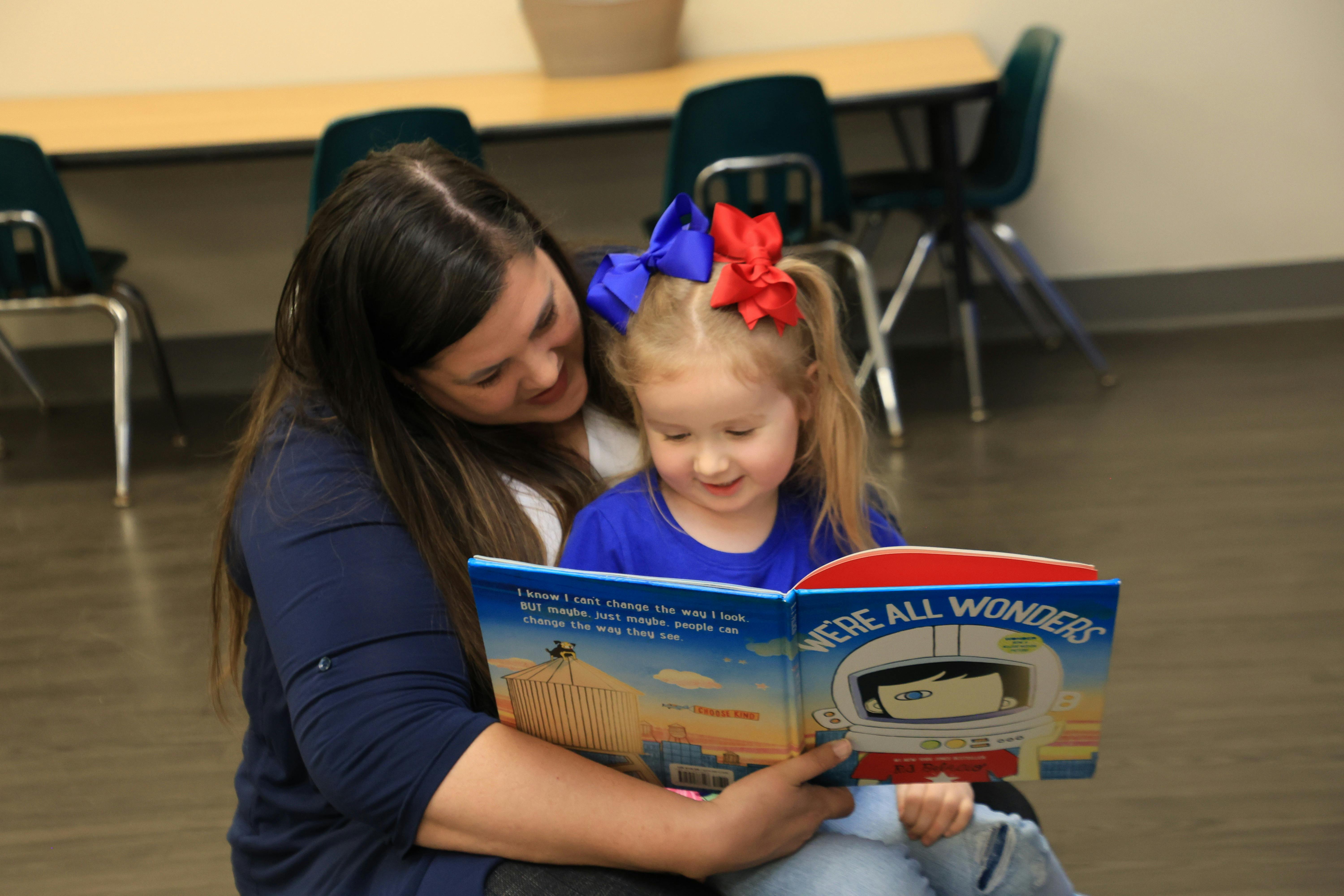Person and child reading a book together