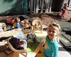 Child smiling at camera with toys and other children in background