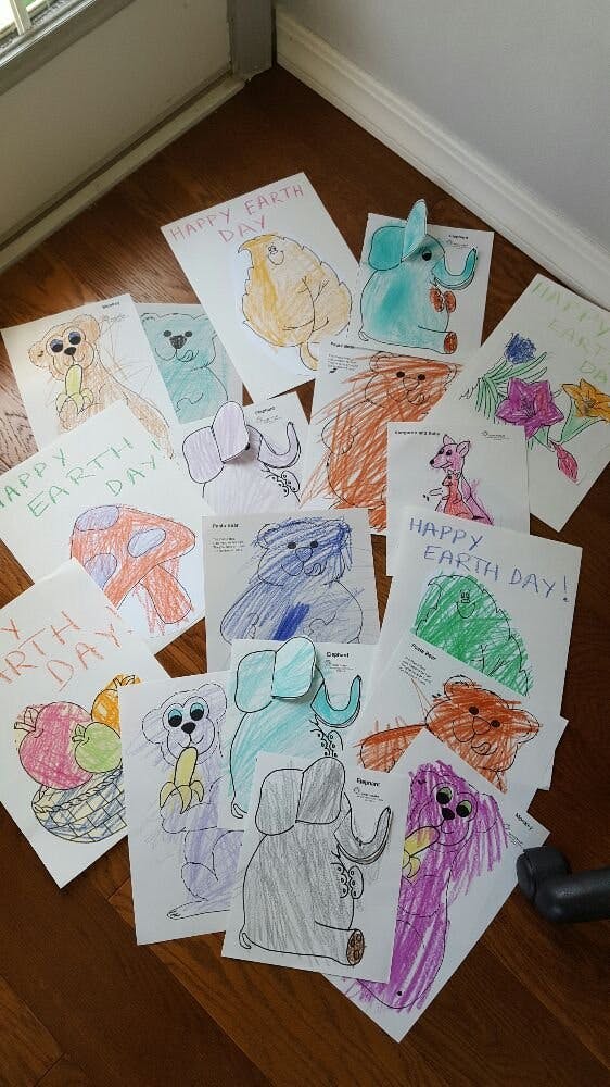 Children's drawings of animals and fruit, some with "Happy Earth Day" text