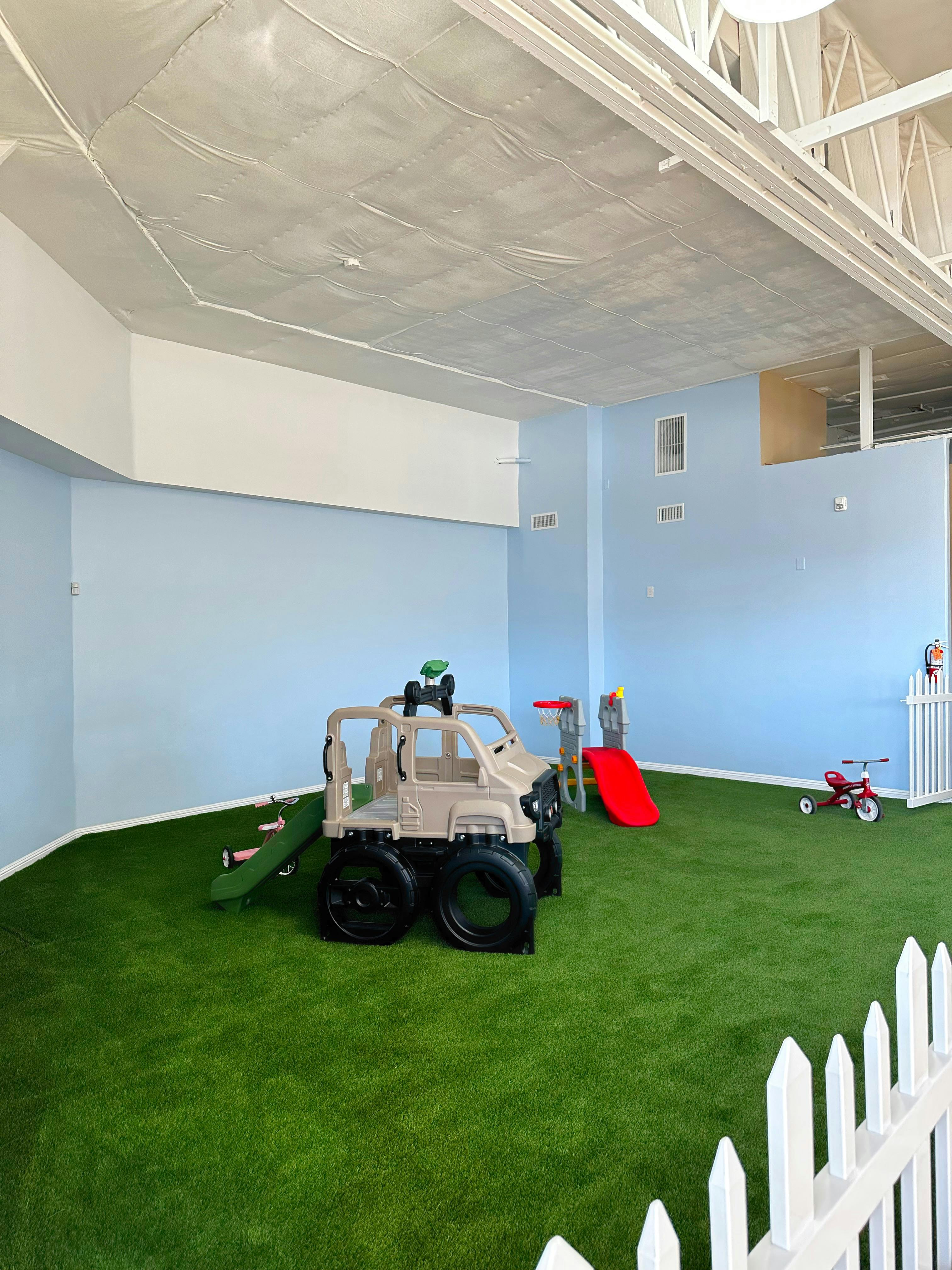Indoor play area with artificial grass, toy truck, and red slide