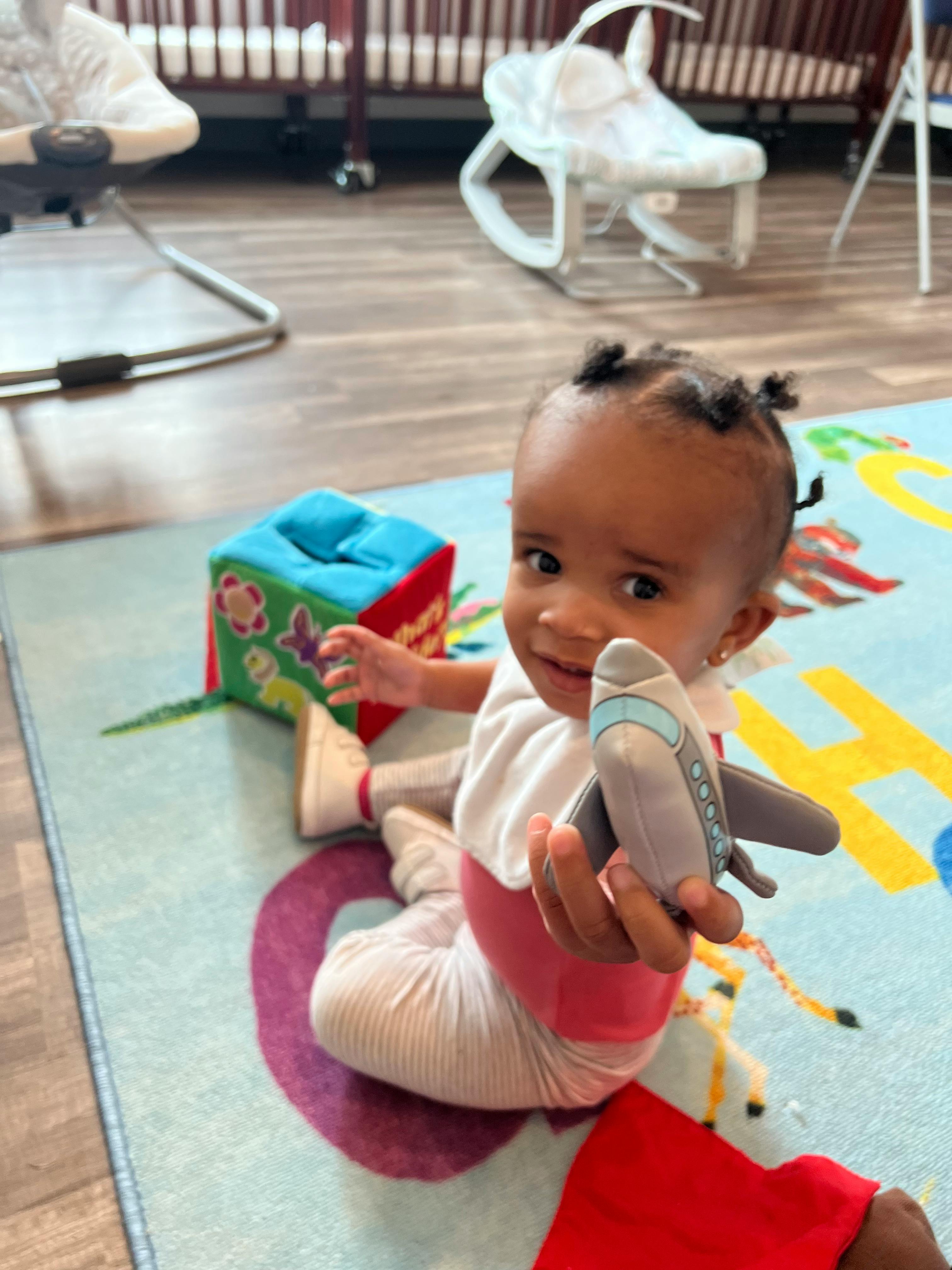 Child sitting on a rug holding a toy airplane