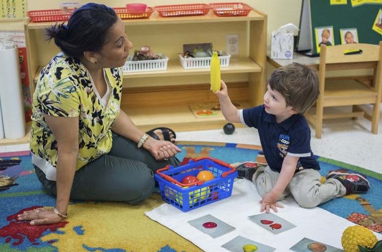 Adult and child playing with toy food and cards on the floor