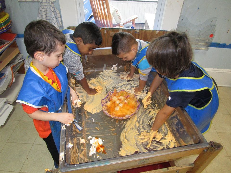 Four children playing with messy materials on a table
