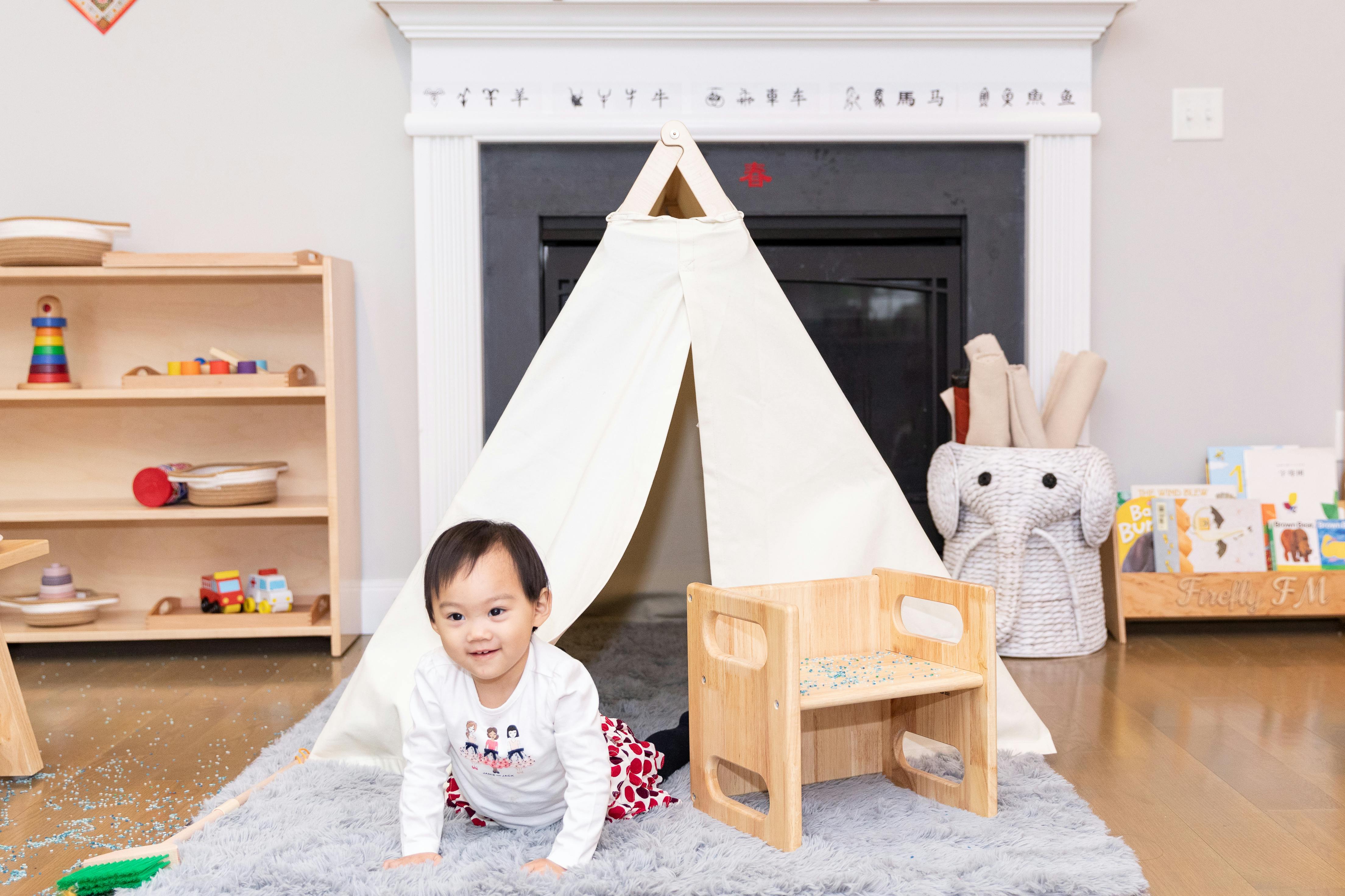 Child crawling on a rug in a room with a play tent