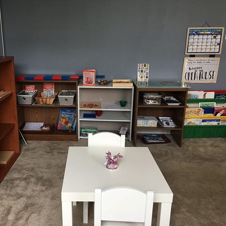 Classroom with small white table and chairs, shelves with books and learning materials
