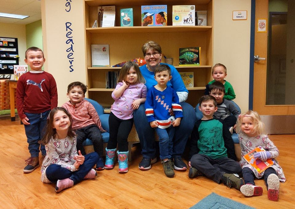 Adult and multiple children posing in a library