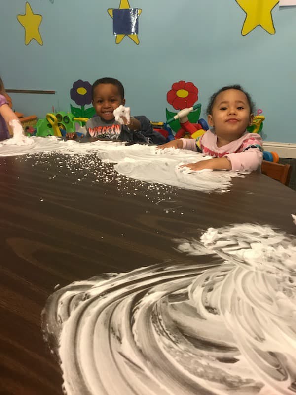 Two children playing with white foam on a table