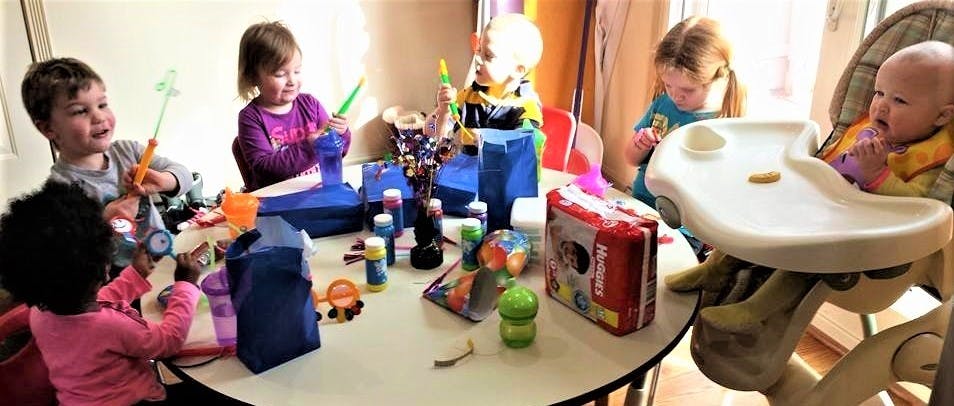 Four children and a baby at a table with art supplies