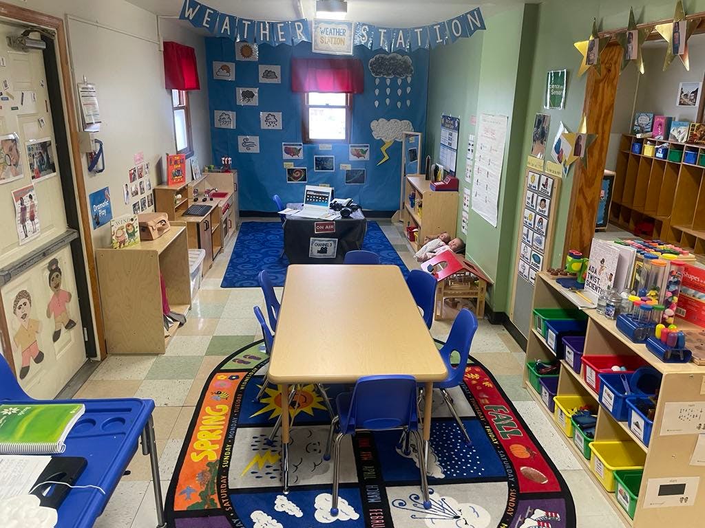 Classroom with a table and chairs, and a weather station display