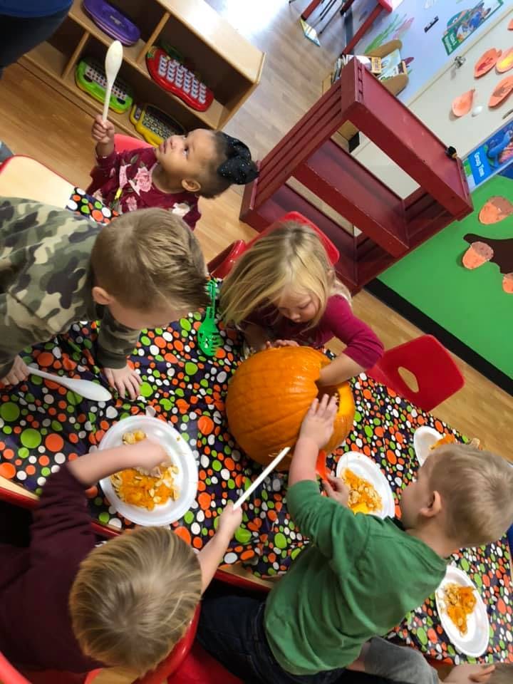 Children carving a pumpkin at a table