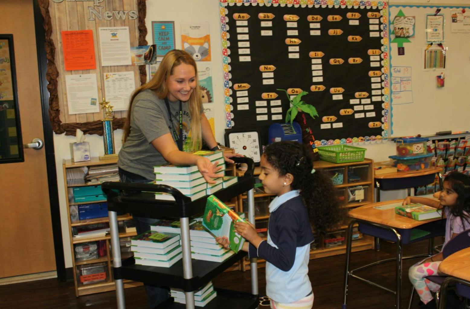 Adult and child exchanging books in a classroom