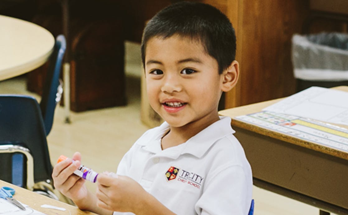 Child holding a glue stick in a classroom