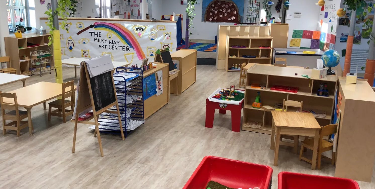 Classroom with small tables, chairs, and shelves
