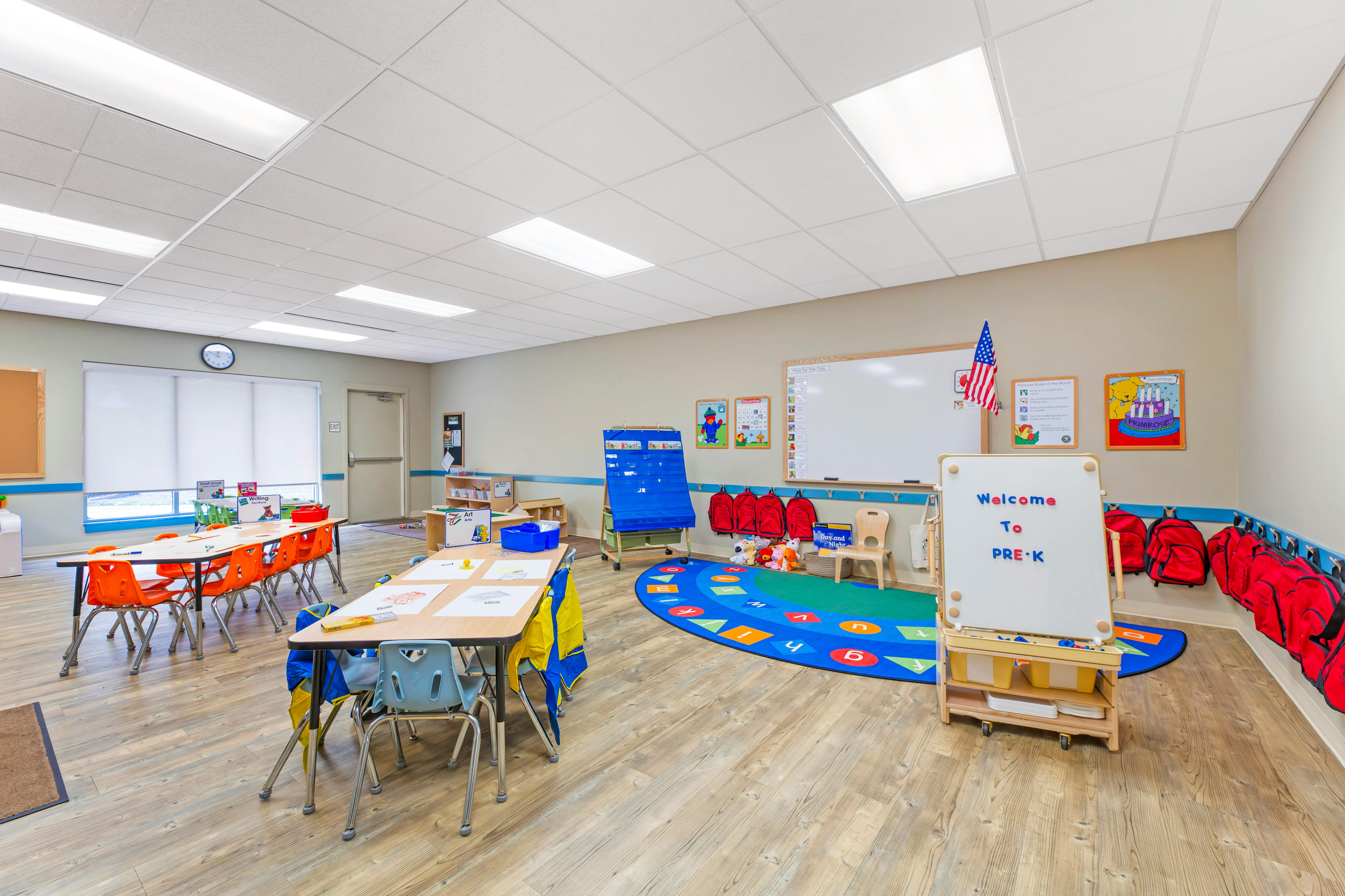Empty colorful preschool classroom with tables, chairs, and learning materials