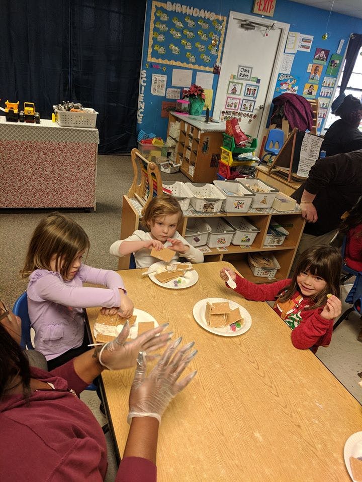 Children and an adult making crafts at a table in a classroom