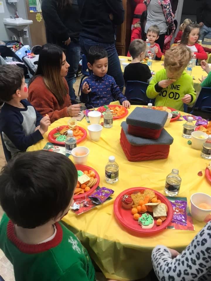 Children and adults gathered around a table with snacks and drinks
