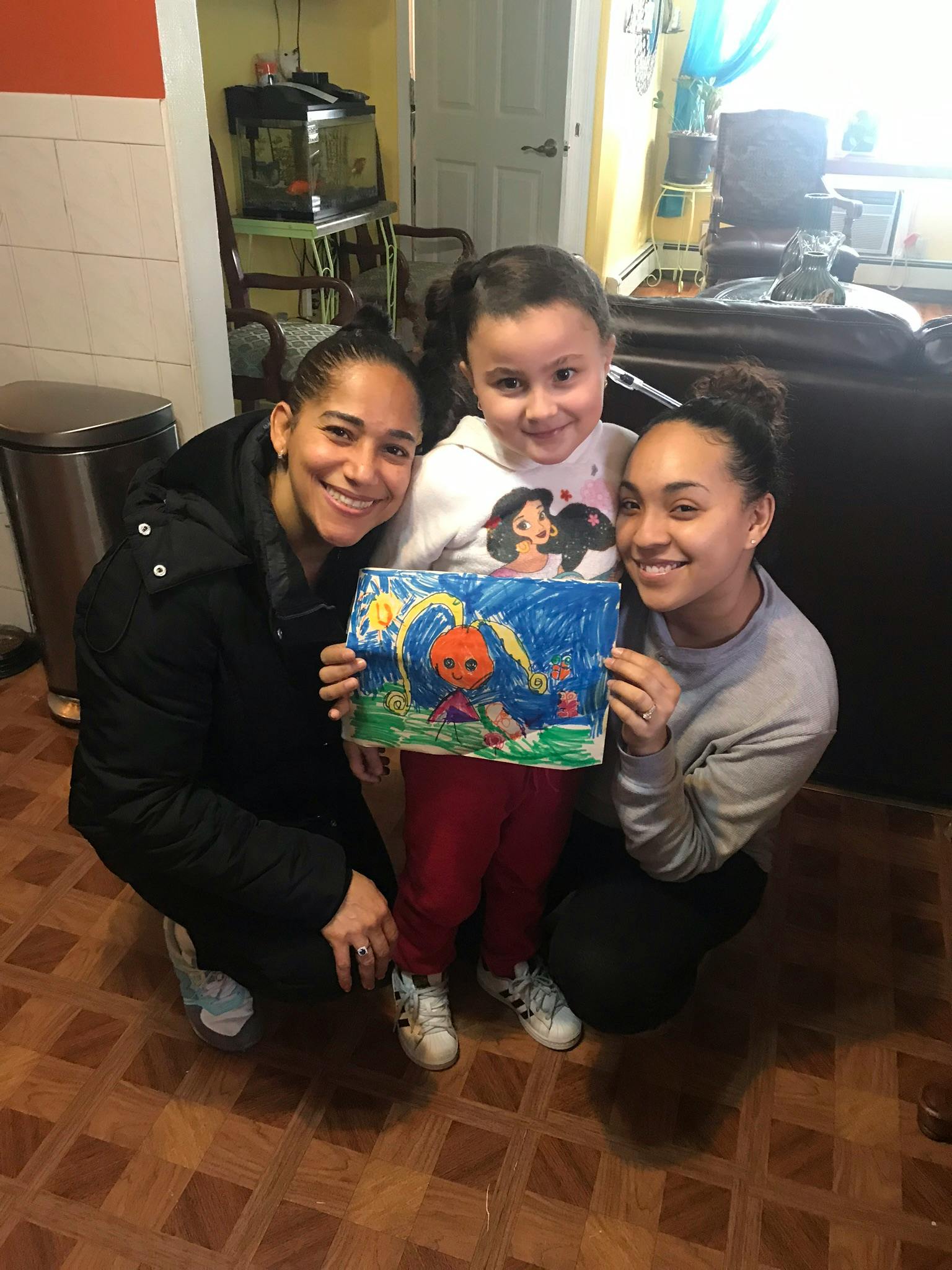 Two people and a child holding up a drawing