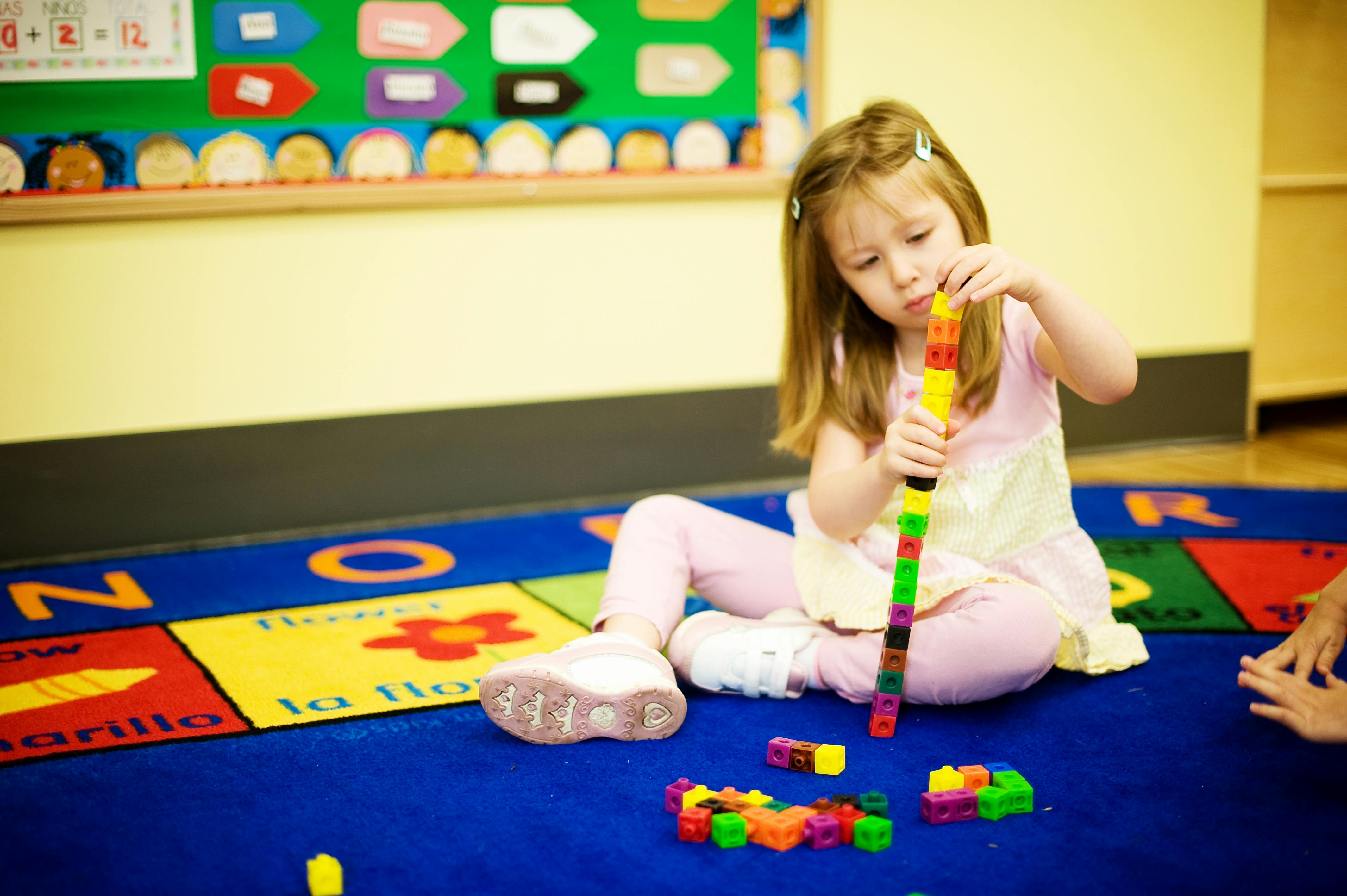 Child building with colorful blocks on a classroom rug
