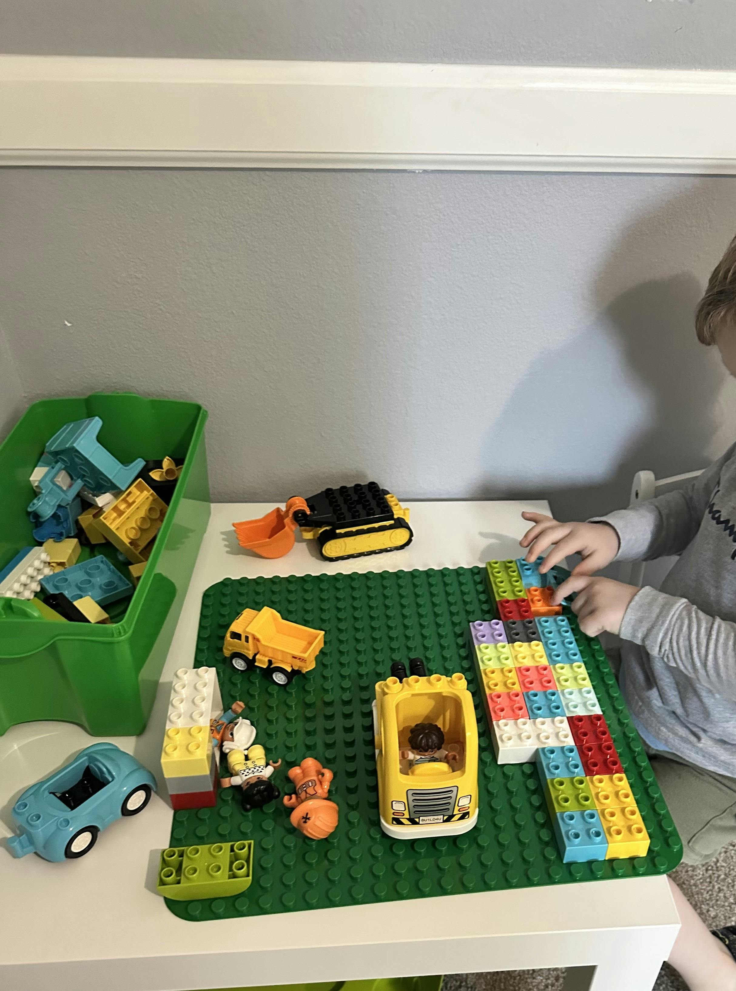 Child playing with colorful building blocks and toy vehicles on a table