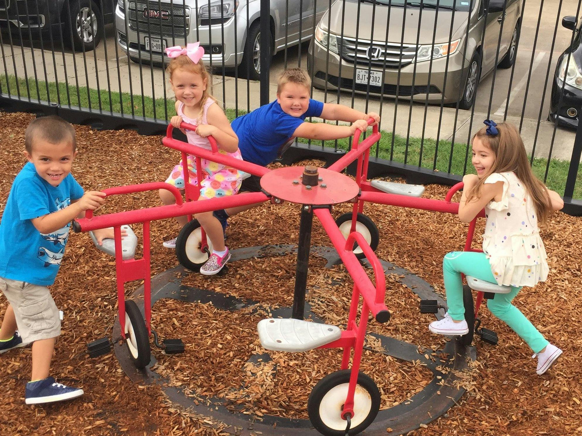 Four children playing on a red merry-go-round