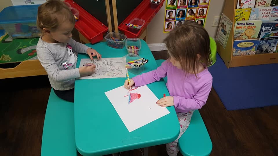 Two children drawing at a small table