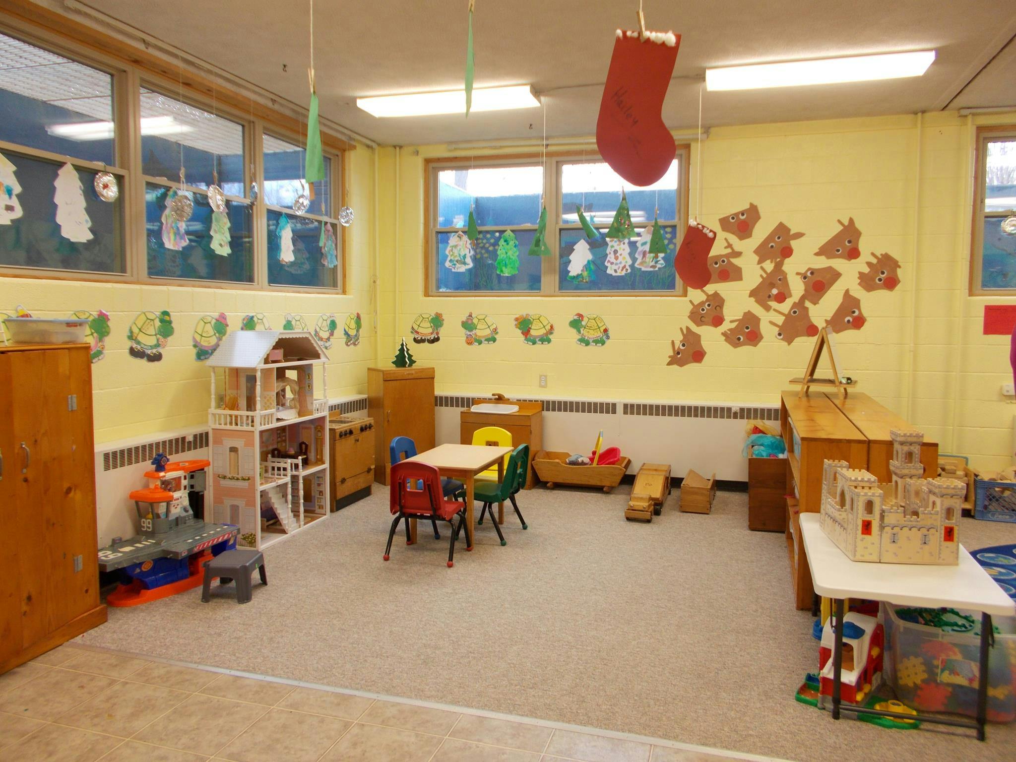 A classroom with small tables and chairs, toys, and decorations