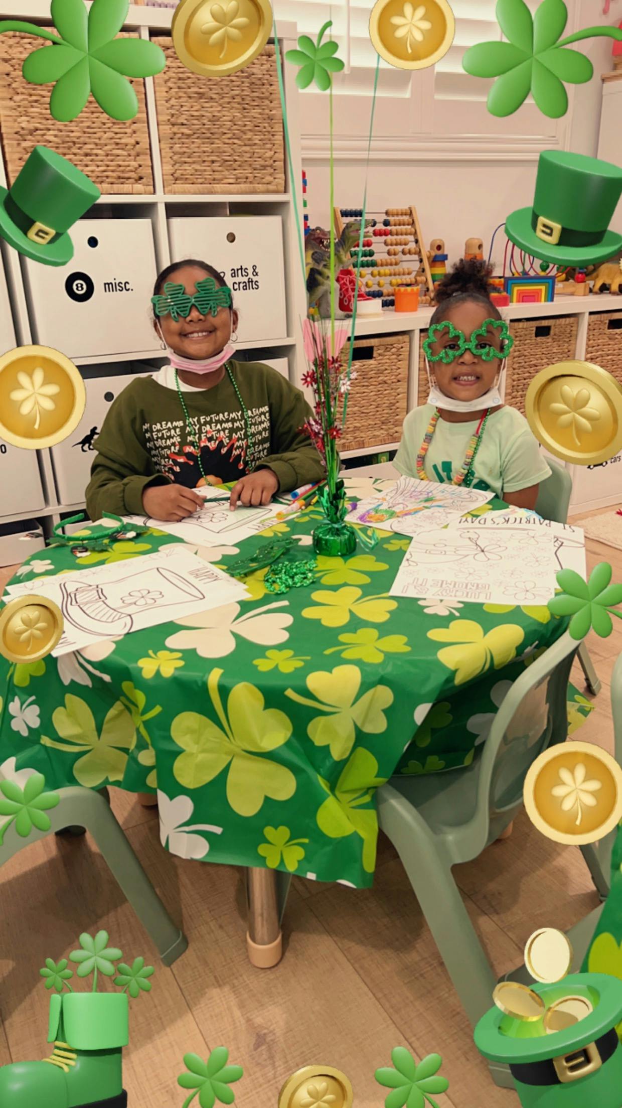 Two children wearing shamrock glasses at a table with a shamrock tablecloth