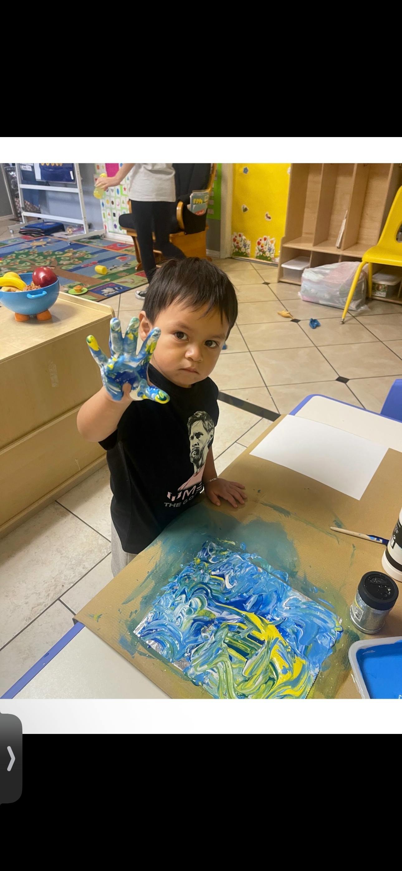 Child showing a hand covered in blue and yellow paint