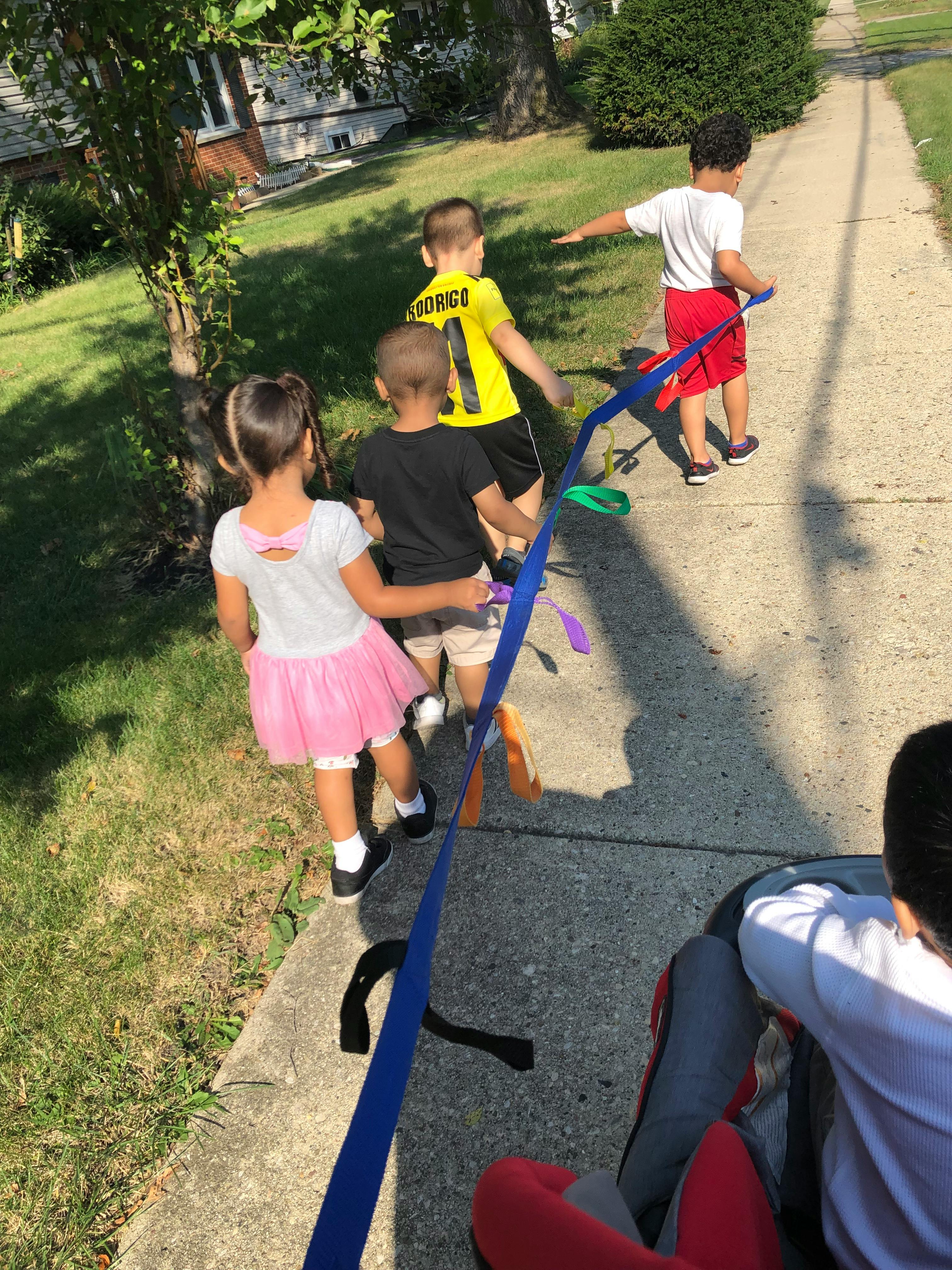 Children walking on a sidewalk with a blue ribbon