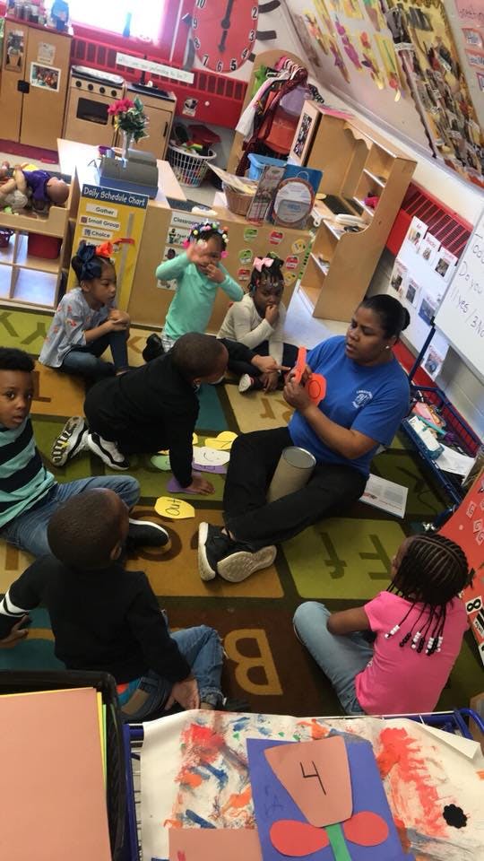 Adult and children sitting on a rug in a classroom