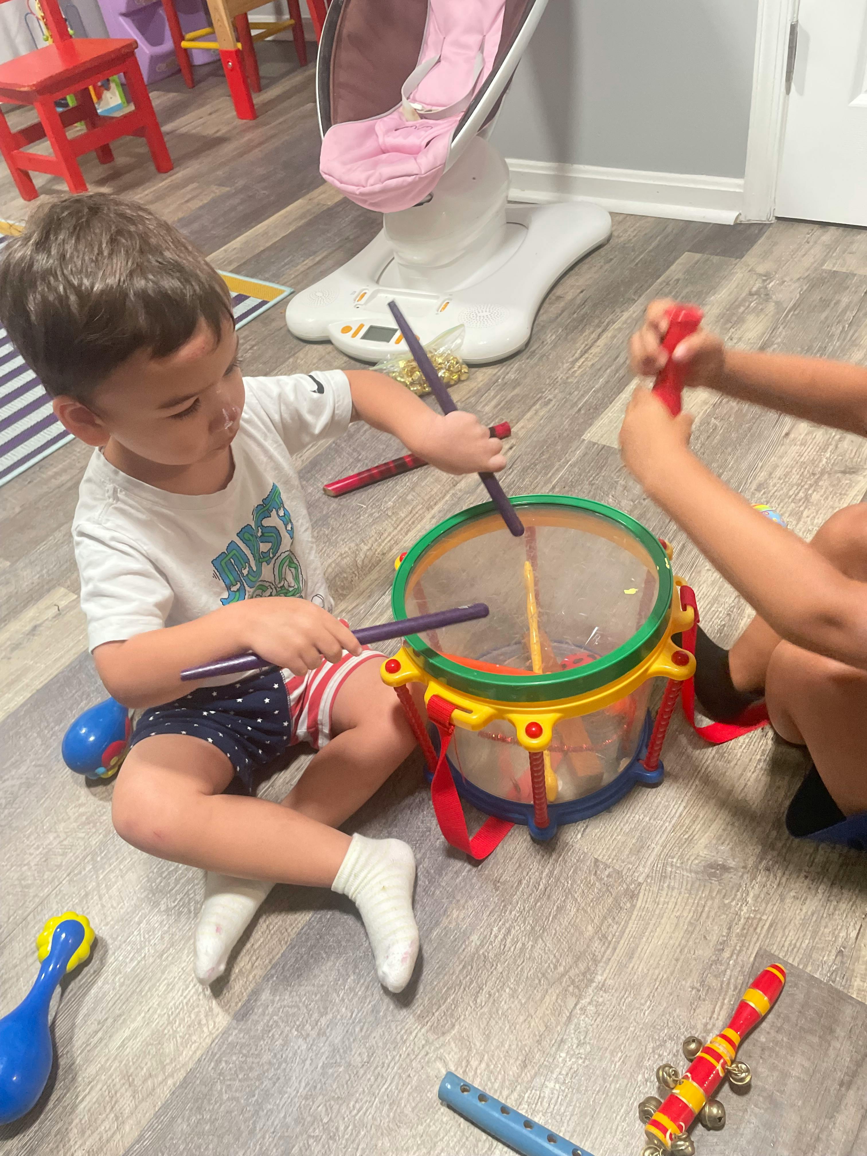 Child playing a toy drum with drumsticks