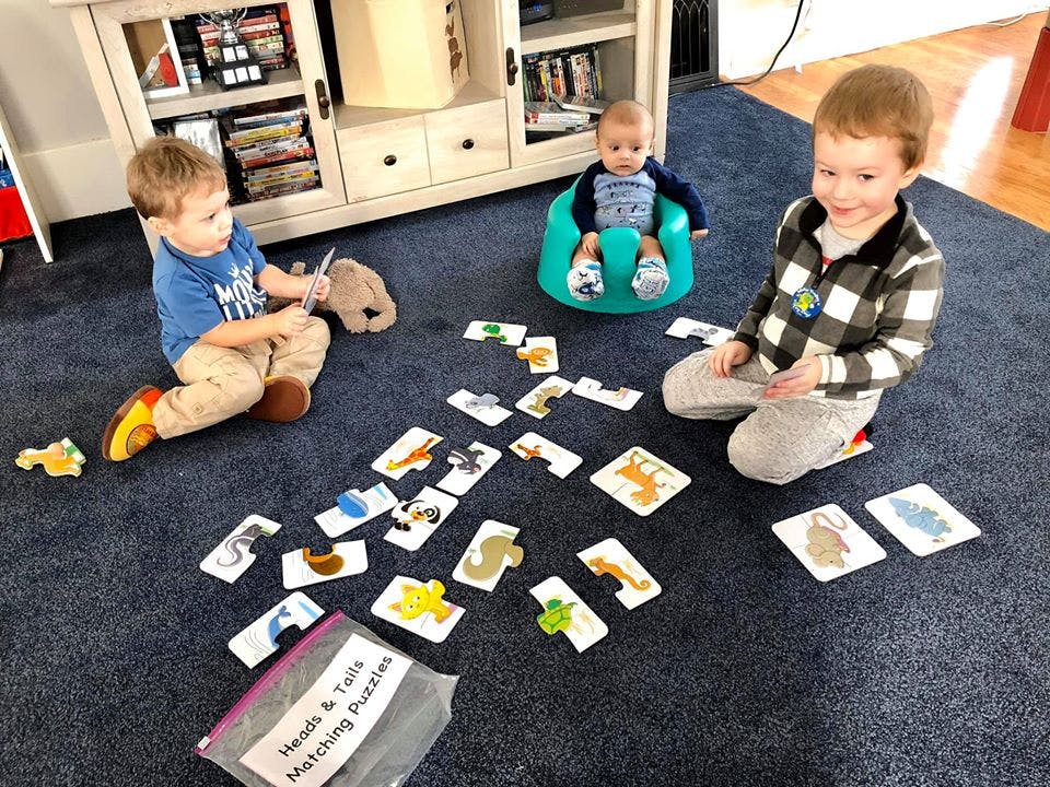 Three children playing with matching puzzles on a carpeted floor