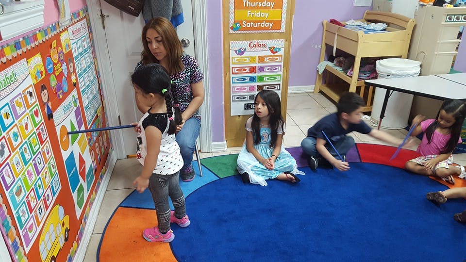 Adult and children in a classroom looking at a wall chart