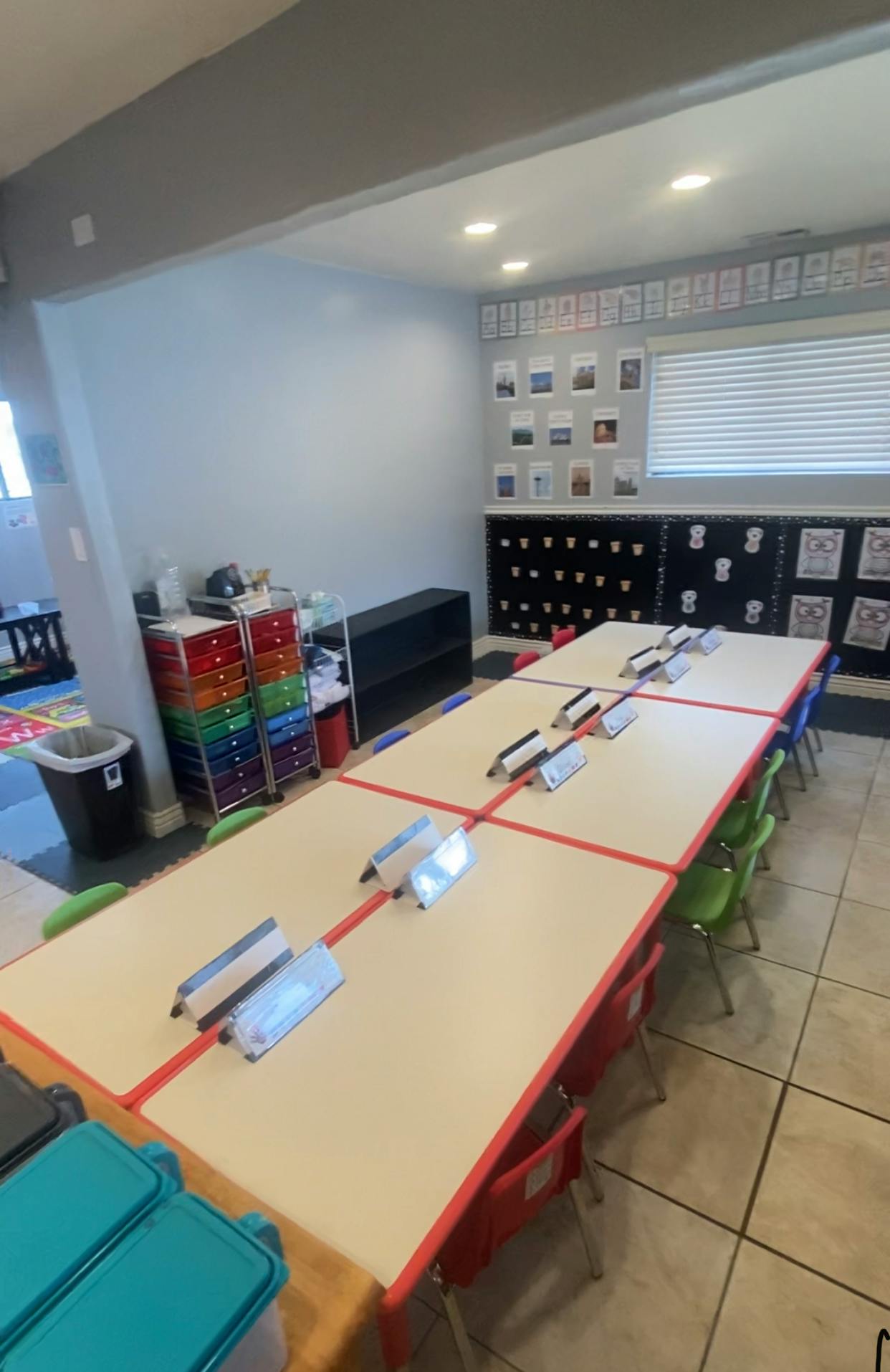 Classroom with long tables and chairs, storage units, and wall decorations