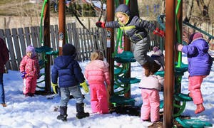 Children playing on playground equipment in the snow