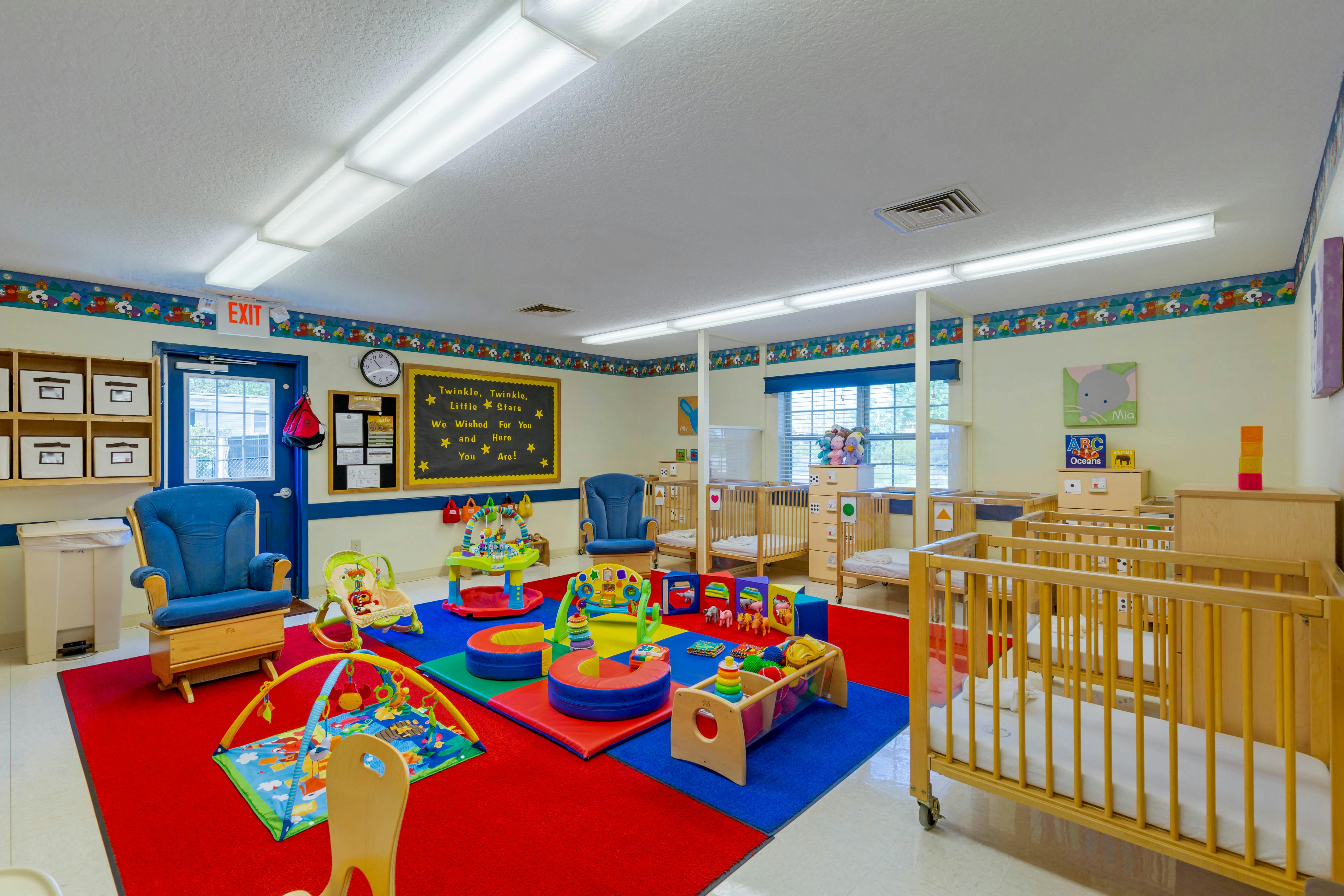 Classroom or daycare with cribs, playmats, chairs, and play equipment