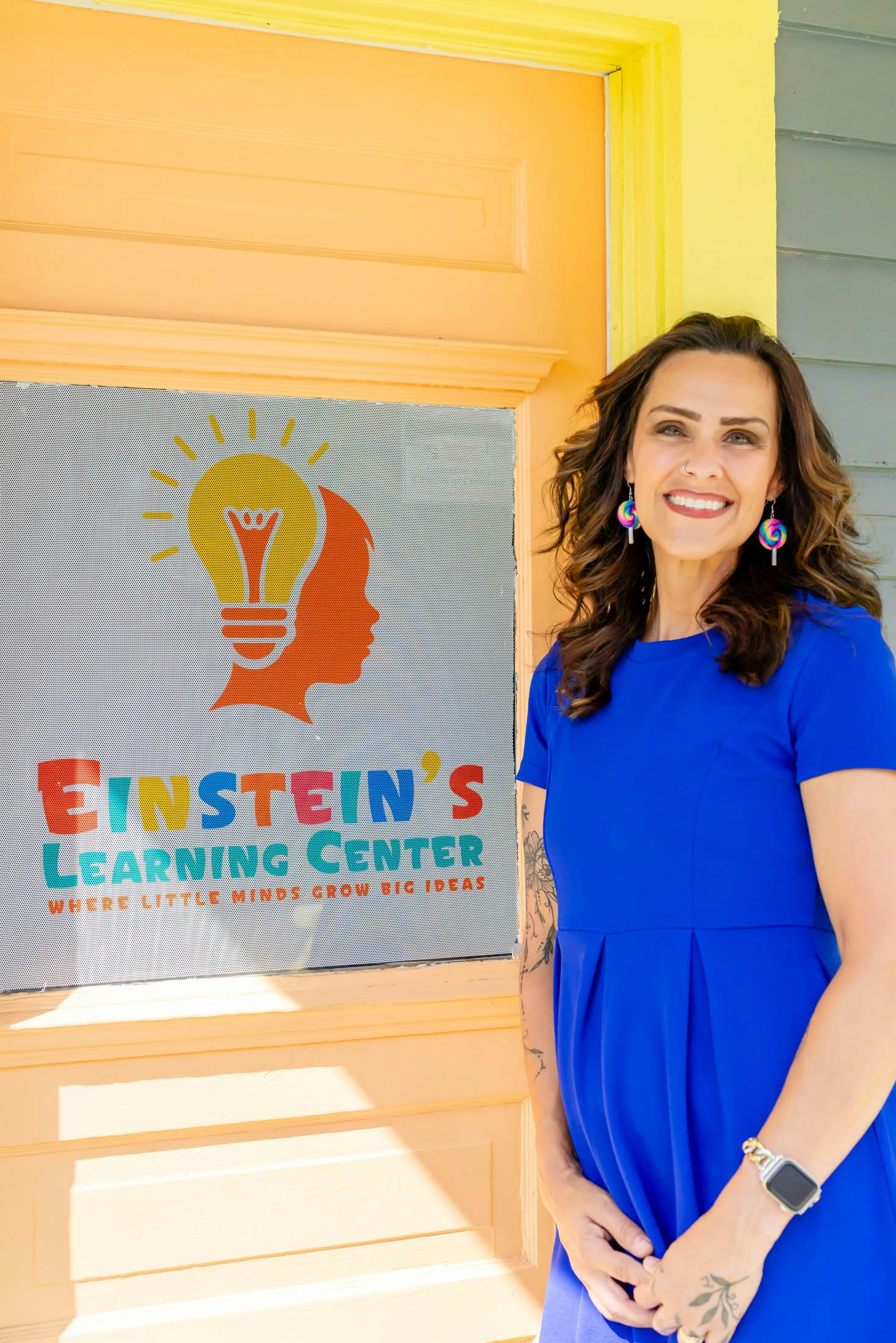 Person in blue dress standing next to a sign for Einstein's Learning Center