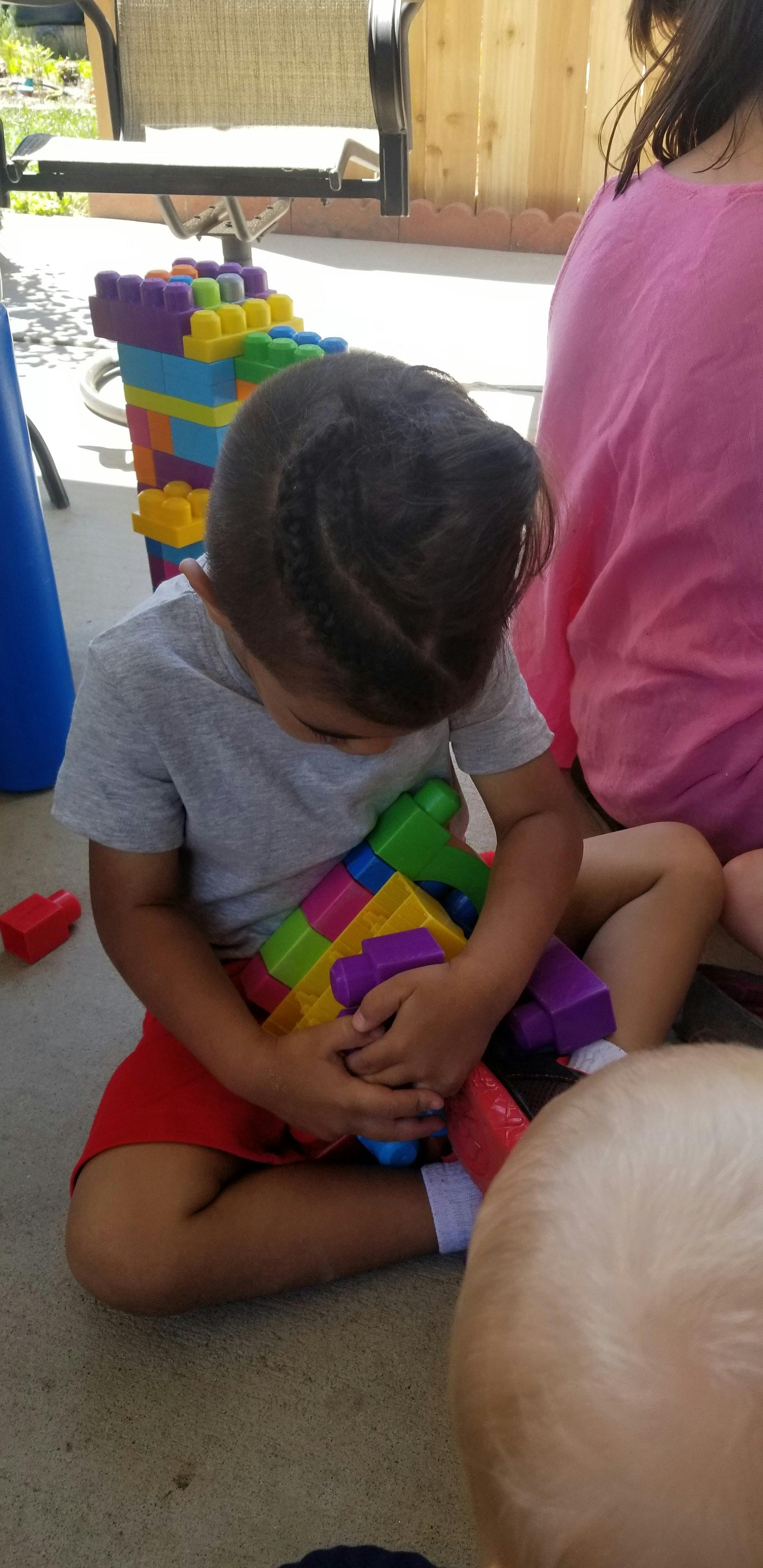 Child sitting on the ground holding colorful building blocks