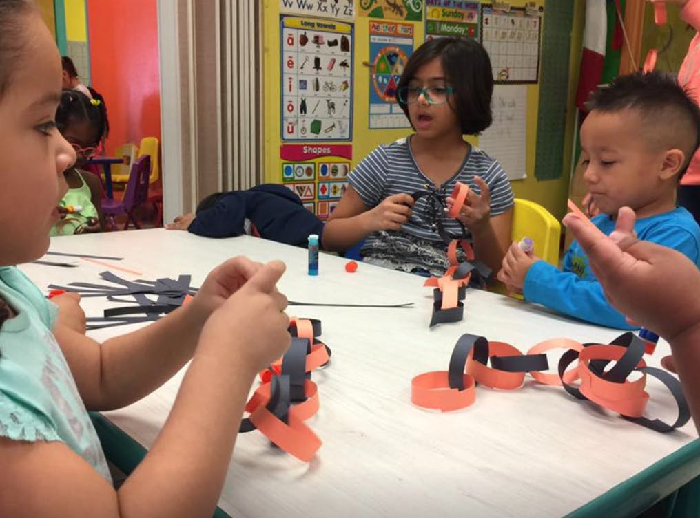 Children making paper chains at a table