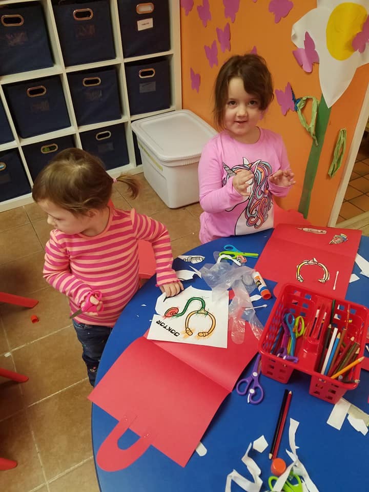Two children at a blue table with craft supplies